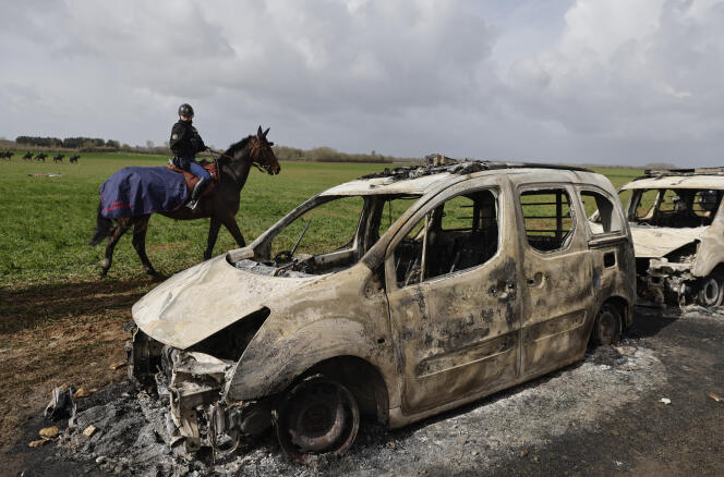 A mounted police officer rides past burned-out police vehicles next to the construction site of an agricultural reservoir after clashes with protesters in Sainte-Soline, western France, March 26, 2023. 