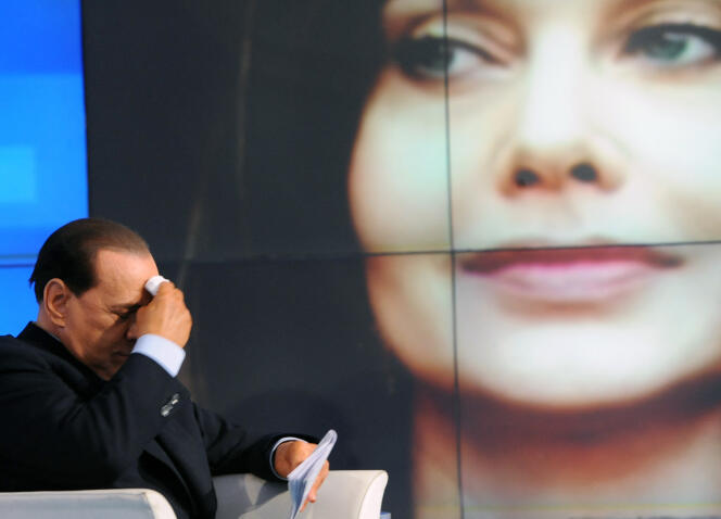 Silvio Berlusconi and the portrait of his wife Veronica Lario in the background, during the recording of a TV program in Rome on May 5, 2009.