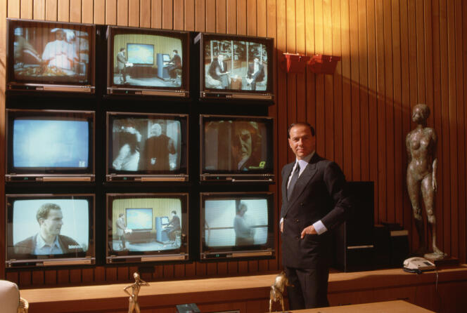 Silvio Berlusconi, next to a set of television sets, in 1986.