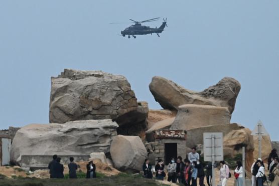 Un helicóptero militar chino sobrevuela a los turistas sobre el estrecho de Taiwán en la isla de Pingtan, el punto más cercano a Taiwán, en la provincia de Fujian, sureste de China, el 7 de abril de 2023.