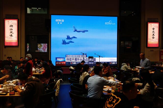 In a Beijing restaurant, a giant screen broadcasts images of a Chinese military aircraft participating in a combat readiness patrol and training exercise 