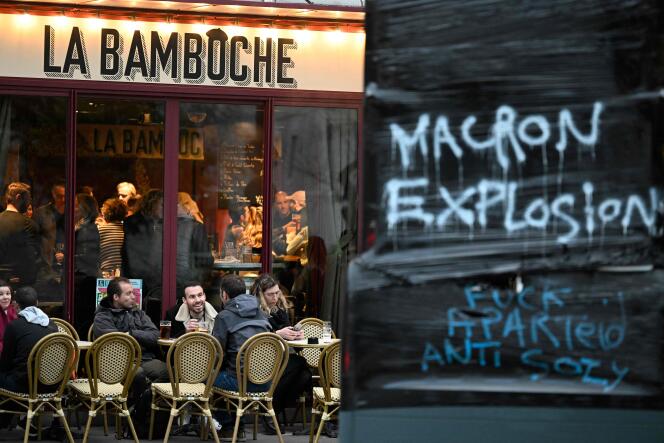 Costumers sit on a terrace next to a hand-written message reading 