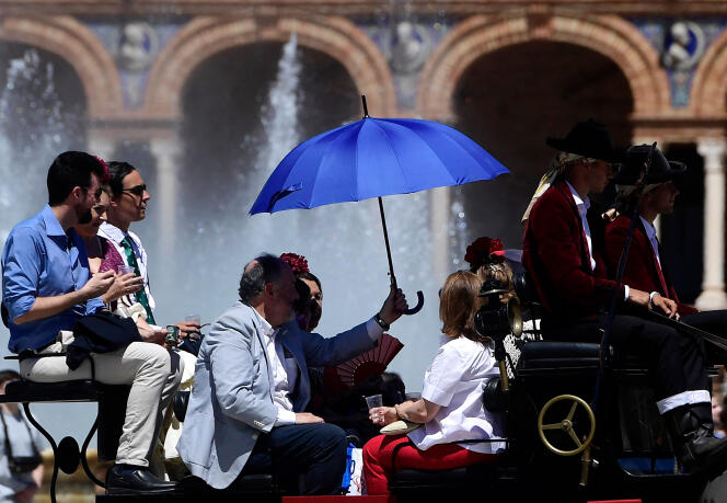 A group of people on a horse-drawn carriage protect themselves from the sun with an umbrella in Seville on April 26, 2023, as Spain is bracing for an early heat wave.