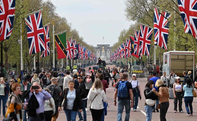 People walk beneath flags of the Union and Commonwealth along The Mall, towards Buckingham Palace, in central London, on April 30.