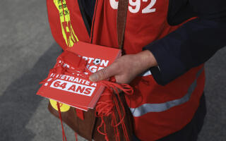 An unionist distributes red cards and whistles to show their anger against the pension reform, ahead of the French Cup final opposing Nantes to Toulouse, outside the Stade de France stadium in Saint-Denis, outside Paris, Saturday, April 29, 2023. French President Emmanuel Macron is expected to attend the match. (AP Photo/Aurelien Morissard)