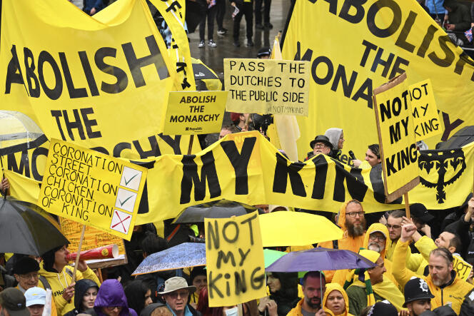 Des manifestants brandissent des pancartes le long du parcours de la procession du couronnement à Londres, le 6 mai 2023. La police a arrêté plus de vingt manifestants avant la cérémonie, dont six antimonarchistes et plusieurs militants écologistes qui souhaitaient protester sur le parcours royal.