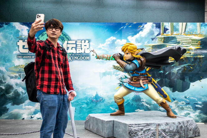 Un client d’un magasin de jeux vidéos pose avec une statue inspirée du jeu vidéo « The Legend of Zelda : Tears of the Kingdom ». A Tokyo, le 7 mai 2023.