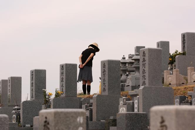 2016年8月13日、姫路市の名山霊園にある先祖の墓の前で祈る女性。