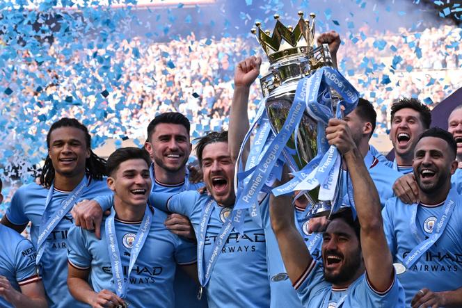 O meio-campista Ilkay Gundogan levanta o troféu da Premier League enquanto os jogadores do Manchester City comemoram seu título após o jogo contra o Chelsea, no Etihad Stadium em Manchester em 21 de maio de 2023.