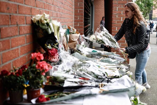 Une femme dépose un bouquet de fleurs devant le commissariat de police de Roubaix (Nord), mardi 23 mai 2023. 