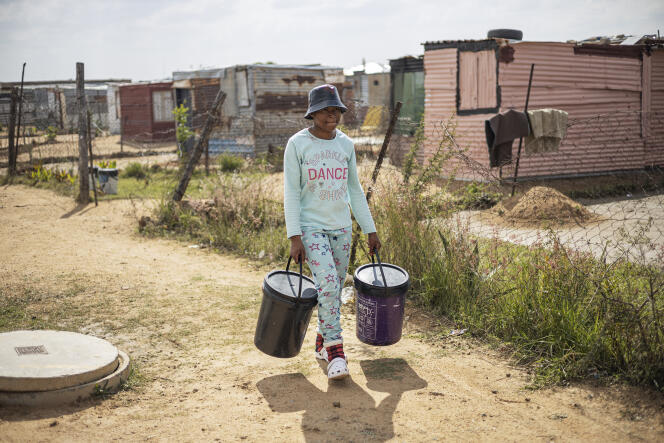 Une femme porte des seaux d’eau à Hammanskraal, en Afrique du Sud, le 23 mai 2023.