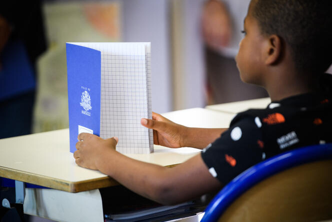 A student holds a notebook offered by the mayor of Marseille during the start of the school year at the Révolution-Jet d'Eau school, in Marseille, on September 1, 2022.