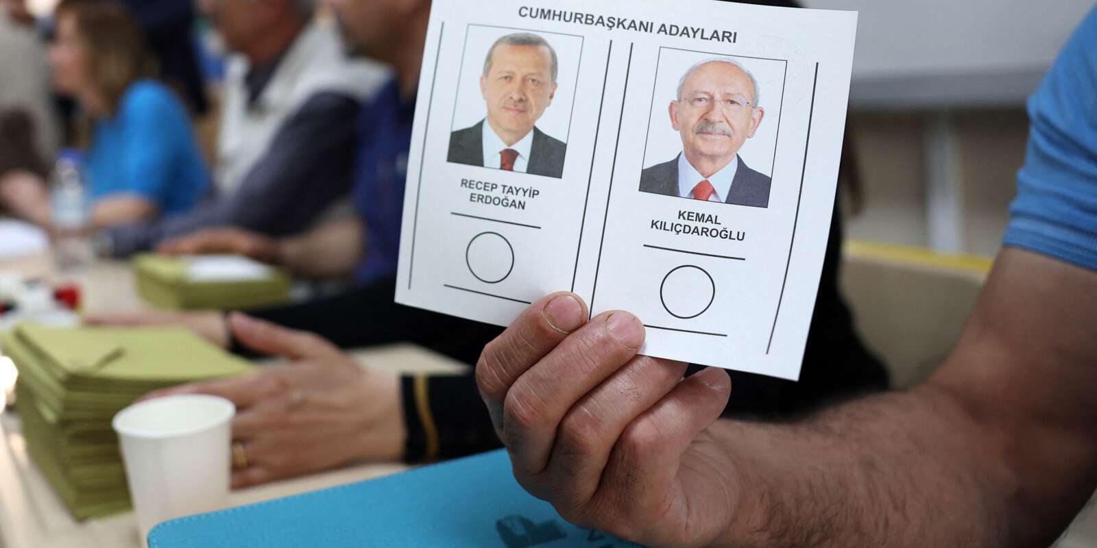 Un fonctionnaire électoral montre un bulletin de vote sur lequel figurent les deux candidats, Recep Tayyip Erdogan (G) et Kemal Kilicdaroglu, dans un bureau de vote lors du second tour de l’élection présidentielle, à Ankara, le 28 mai 2023.