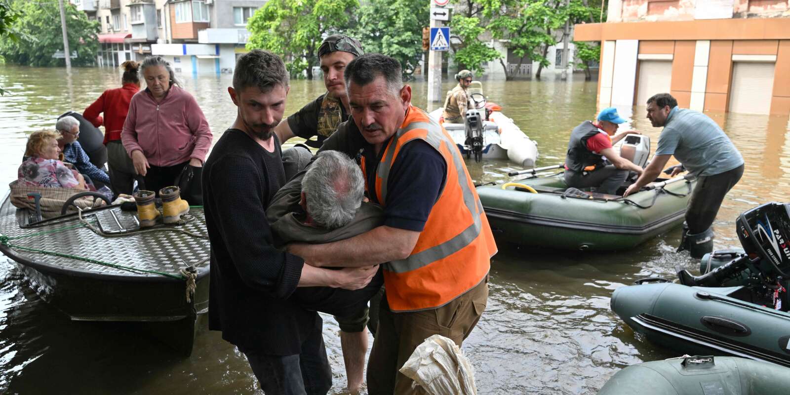 Des volontaires aident un résident handicapé lors de l’évacuation d’une zone inondée à Kherson, le 8 juin 2023, à la suite des dommages subis au barrage de Kakhovka.