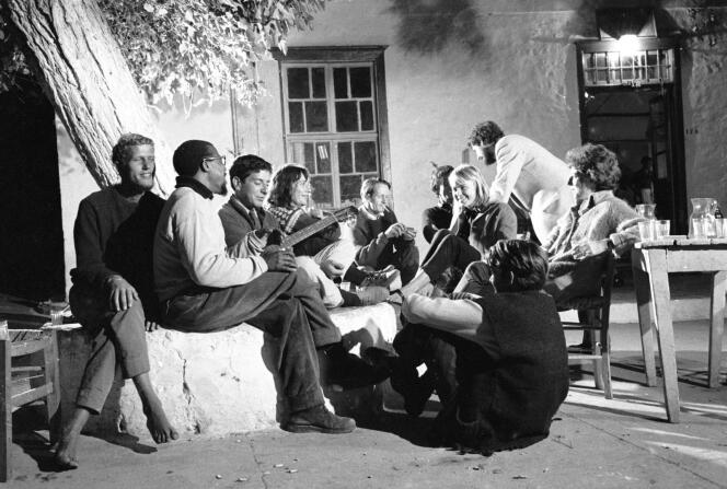 Devant sa maison à Hydra, en Grèce, Leonard Cohen à la guitare, en compagnie de la blonde Marianne Ihlen et de leurs amis, en octobre 1960. 