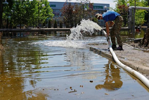 Un miembro del Cuerpo de Ayuda Estudiantil de Rusia bombea agua desde el sótano de un edificio de apartamentos en la ciudad de Hola Prystan en la región de Kherson en un área controlada por Rusia el 17 de junio de 2023.