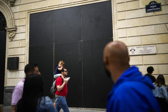 Devant un magasin Apple recouvert de planches de protection, sur l’avenue des Champs-Elysées, à Paris, le 1er juillet 2023.