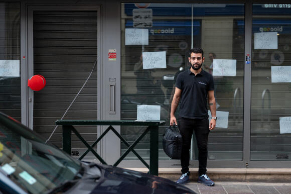 Didier Benouari, 36 ans, patron d’un Cash Converters, devant son magasin le lendemain d’une tentative d’effraction, malgré les affichettes « le magasin est vide » collées sur toute la vitrine, à Nanterre, le 1er juillet 2023.
