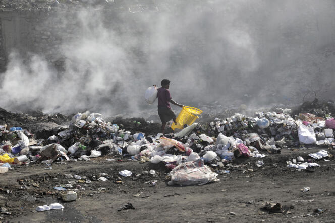 A woman scours the drains for salvageable items, in Port-au-Prince, the capital of Haiti, on July 1, 2023.