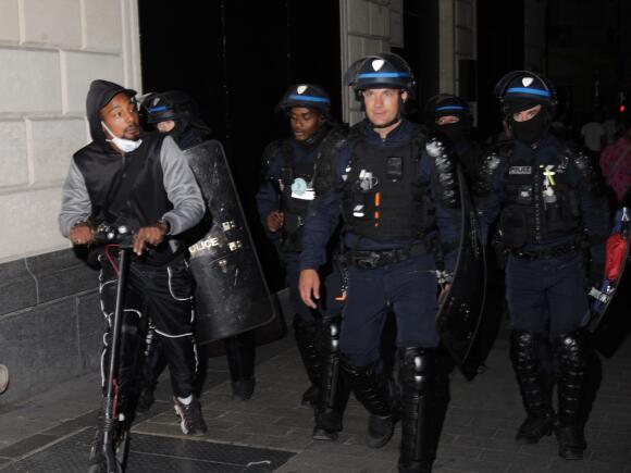 Des policiers remontent les Champs Elysées en déplaçant des manifestants et des touristes, à Paris, dans la nuit du 1er au 2 juillet 2023.