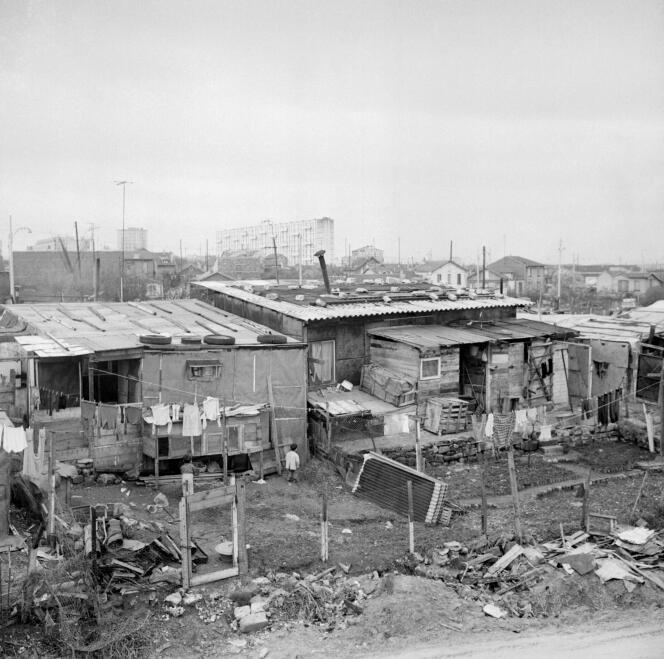 Le bidonville de Nanterre, où vivaient un grand nombre de familles d’immigrés algériens, le 24 mars 1964. A l’arrière-plan, les grands ensembles d’immeubles HLM.