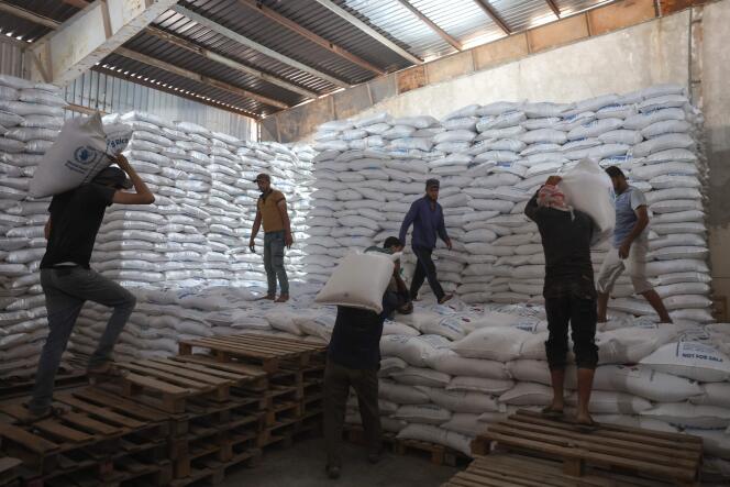Des travailleurs déchargent des sacs d’aide dans un entrepôt près du poste frontière syrien de Bab Al-Hawa, le 10 juillet 2023.