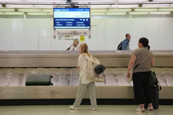 Travelers wait for baggage in Denver International Airport Thursday, July 13, 2023, in Denver. (AP Photo/David Zalubowski)