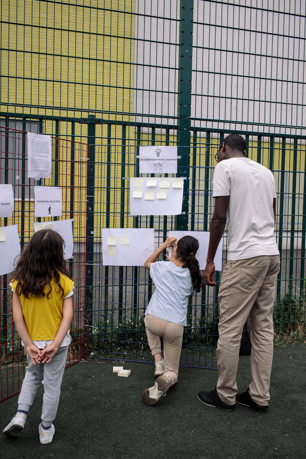 Des habitants écrivent ce qu’ils espèrent pour leur ville, lors de la fête du quartier du Petit-Nanterre, à Nanterre, le 13 juillet 2023.