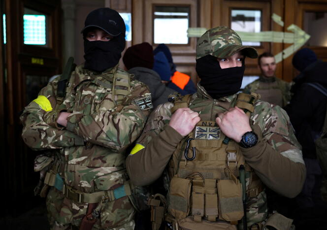 Deux combattants étrangers originaires du Royaume-Uni posent avant de partir vers la ligne de front dans l’est de l’Ukraine, à la gare de Lviv, le 5 mars 2022. 