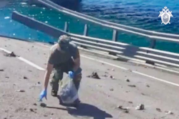 Ein Ermittlungsbeamter sammelt Hinweise auf eine Brücke auf der Krim, die am 17. Juli 2023 über Nacht durch eine Explosion beschädigt wurde.