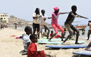 La surfeuse sénégalaise Khadija Sambe donne un cours à des jeunes filles sur une plage de Dakar, en juillet 2023.