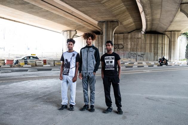 Jany, 18 ans, et ses petits frères, Leny et Lony, 15 ans, à côté de la tour Pleyel, à Saint-Denis, le 7 juillet 2023. « Je trouve que c’est un grand événement pour Paris et pour ici, Saint-Denis, du côté de Pleyel. Il va y avoir du travail, aussi, j’espère, et des logements normalement. Ça va nous aider pour l’avenir. J’espère y assister en tant que bénévole dans le cadre de mon BPJES. (brevet professionnel de la jeunesse, de l’éducation populaire et du sport). »