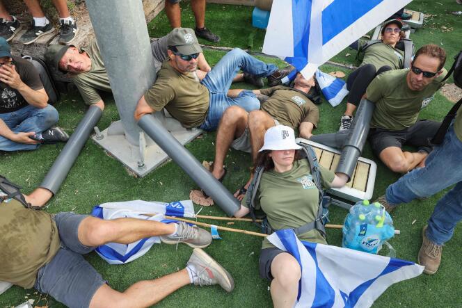Des militants du groupe Frères et sœurs d’armes forment une chaîne humaine afin de bloquer l’entrée principale du quartier général de l’armée israélienne à Tel-Aviv, lors d’une « journée de résistance » contre le projet de loi de réforme judiciaire du gouvernement israélien, le 18 juillet 2023.
