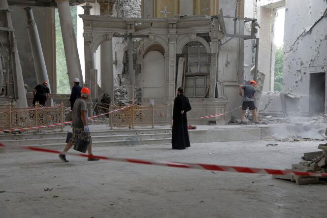 Des volontaires déblaient des débris dans la cathédrale de la Transfiguration, à Odessa, gravement touchée par un tir de missile russe dans la nuit de samedi à dimanche, tandis qu’un prêtre orthodoxe s’y recueille, le 23 juillet 2023.