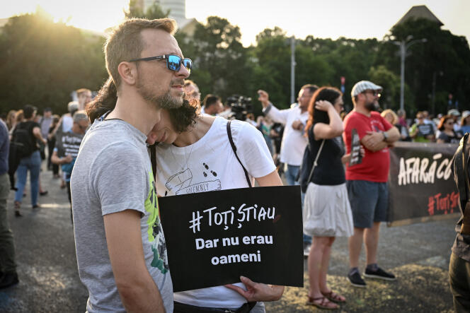 A couple hold a sign reading, in Romanian, 'They all knew, but they weren't human', during a protest against the coalition of ruling parties, outside the Romanian government headquarters, in Bucharest on July 13, 2023.
