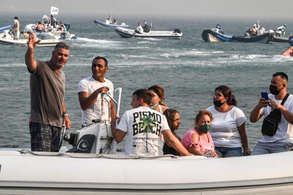 Des civils évacuent par bateau le village côtier de Nea Anchialos, près de la ville continentale grecque de Volos, lors d’un incendie le 27 juillet 2023.