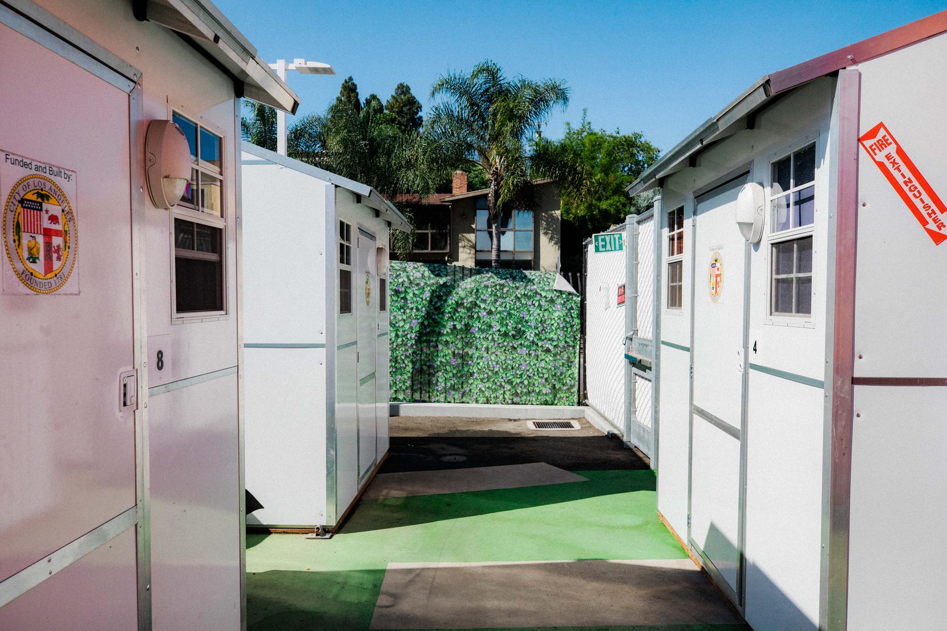 An alley of houses in the Tiny Home Village in Westlake, Los Angeles, on July 19, 2023. The site houses homeless people and is surrounded by a fence to protect it from outside view.