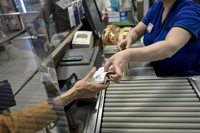 Une hôtesse de caisse remet à une cliente son ticket de caisse après paiement dans un supermarché de Lyon, le 25 juillet 2023.
