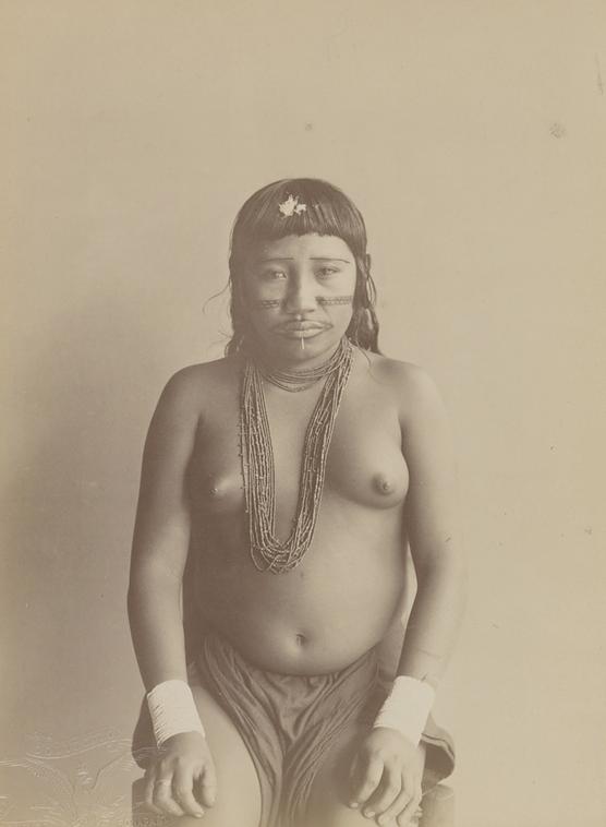 Portrait de Moliko, jeune fille alors âgée d’environ 13 ans, exhibée avec un groupe dit de « Caraïbes » dans la grande serre du Jardin d’acclimatation à Neuilly-sur-Seine, près de Paris, au début du mois de mars 1892. Elle pose assise, de face.