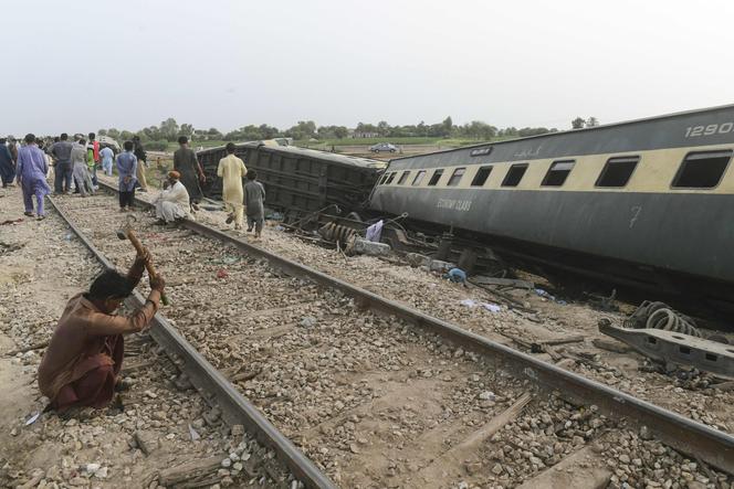 Railway workers repair the tracks next to damaged carriages a day after the derailment of a passenger train in NawabShah on August 7, 2023.