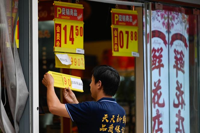 An employee updates prices in a fruit and vegetable store in Beijing, August 9, 2023.