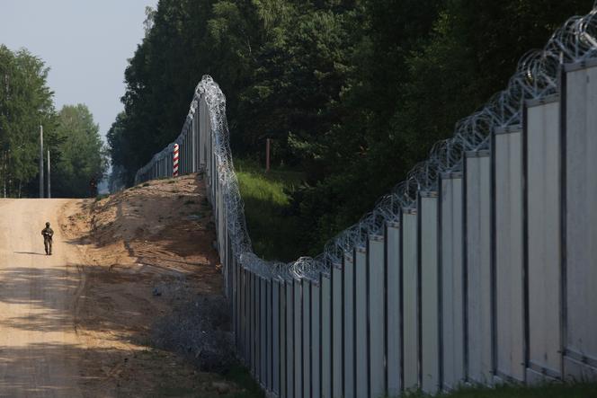  A Polish border guard patrols the area of a built metal wall on the border between Poland and Belarus, near Kuznice, Poland, on June 30, 2022.