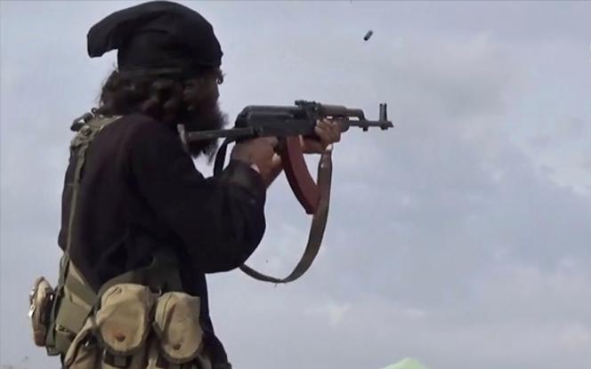 This file frame grab from a video posted online on March 18, 2019, by the Aamaq News Agency, a media arm of the Islamic State group, shows an IS fighter firing his weapon during clashes with the US-backed Syrian Democratic Forces (SDF) fighters, in Baghouz, Syria.