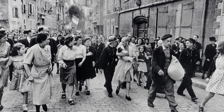 Robert Capa / ICP / Magnum Photos FRANCE. Chartres. August 18th, 1944. French woman, who had had a baby by a Germany soldier, being marched home after being punished by having her head shaved.