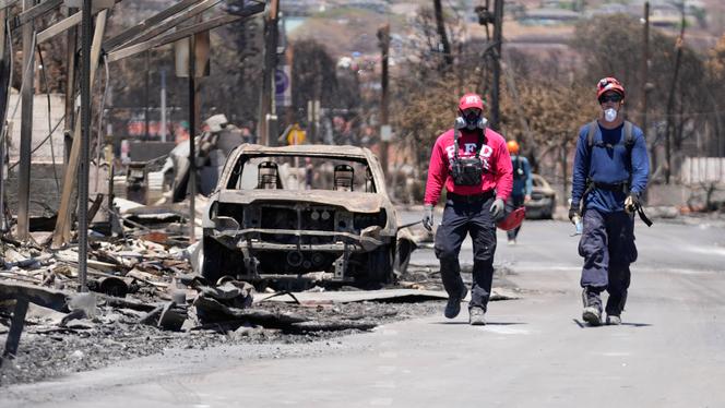 Members of a search-and-rescue team walk along a street, Saturday, August 12, 2023, in Lahaina, Hawaii, following heavy damage caused by wildfire.
