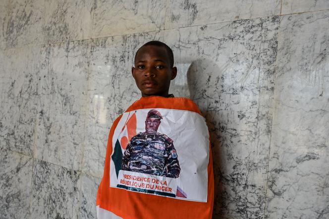 A young man wears a Nigerien flag adorned with the picture of General Abdourahamane Tiani at a concert in support of Niger's National Council for the Safeguard of the Homeland (CNSP) at the General Seyni Kountche Stadium in Niamey on August 13, 2023.
