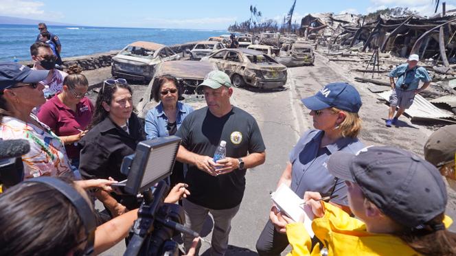 Hawaii Governor Josh Green, center, speaks to reporters during a tour of wildfire damage on Saturday, August 12, 2023, in Lahaina, Hawaii.