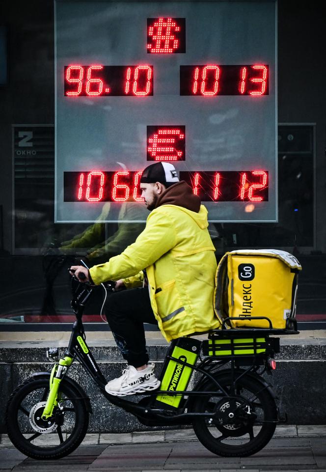 A courier rides past a currency exchange office in Moscow on August 14, 2023. 