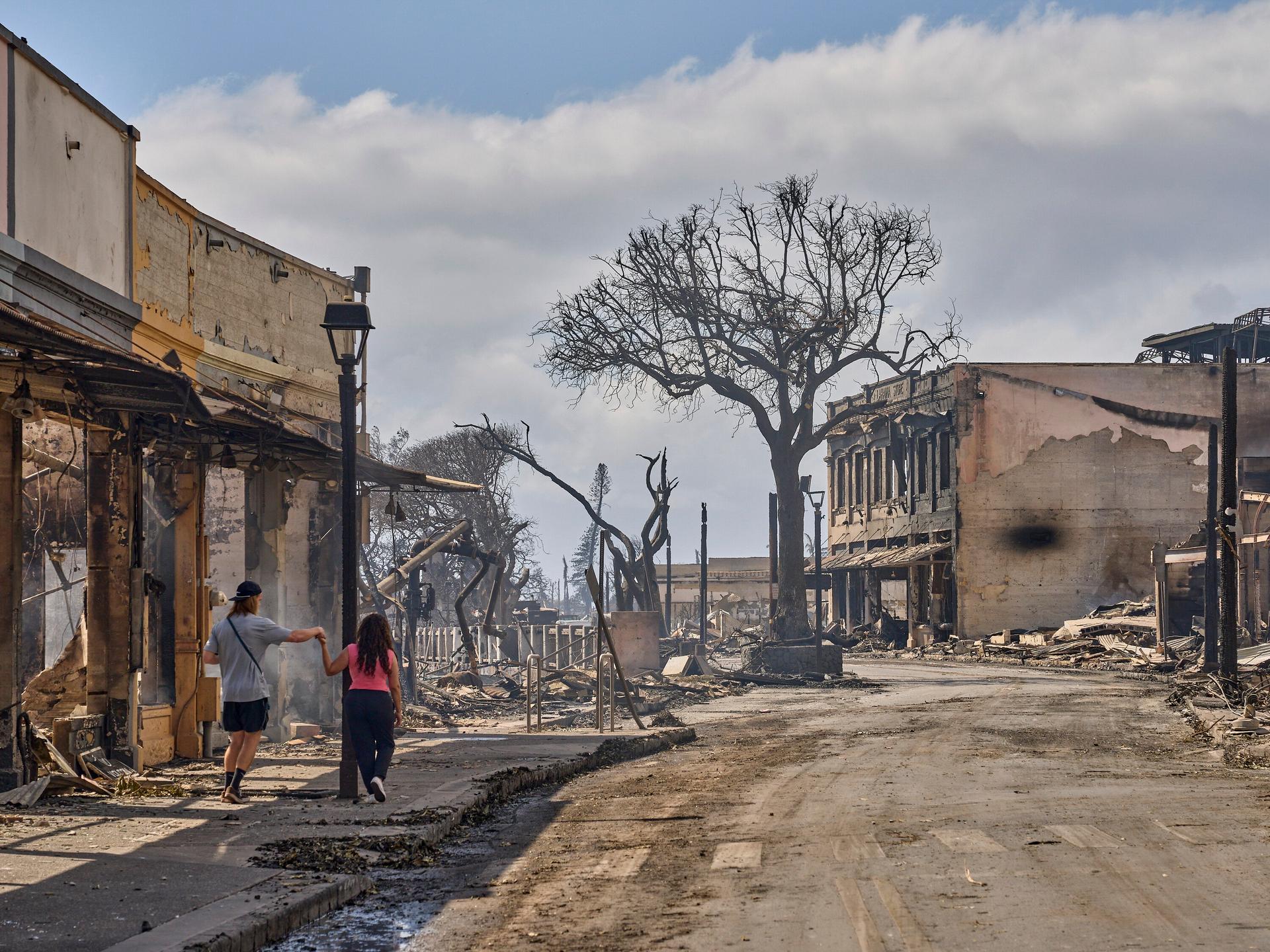 A couple walks past buildings destroyed by fires along Front Street in Lahaina, Maui, Hawaii, August 10, 2023.