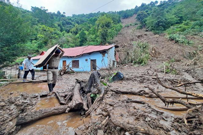 A security personnel carries the belongings of a villager from the site of a landslide after heavy rains at Jadon village in Solan district of India's Himachal Pradesh state on August 14, 2023.